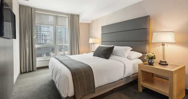 A bed in a hotel room with a view of the city.