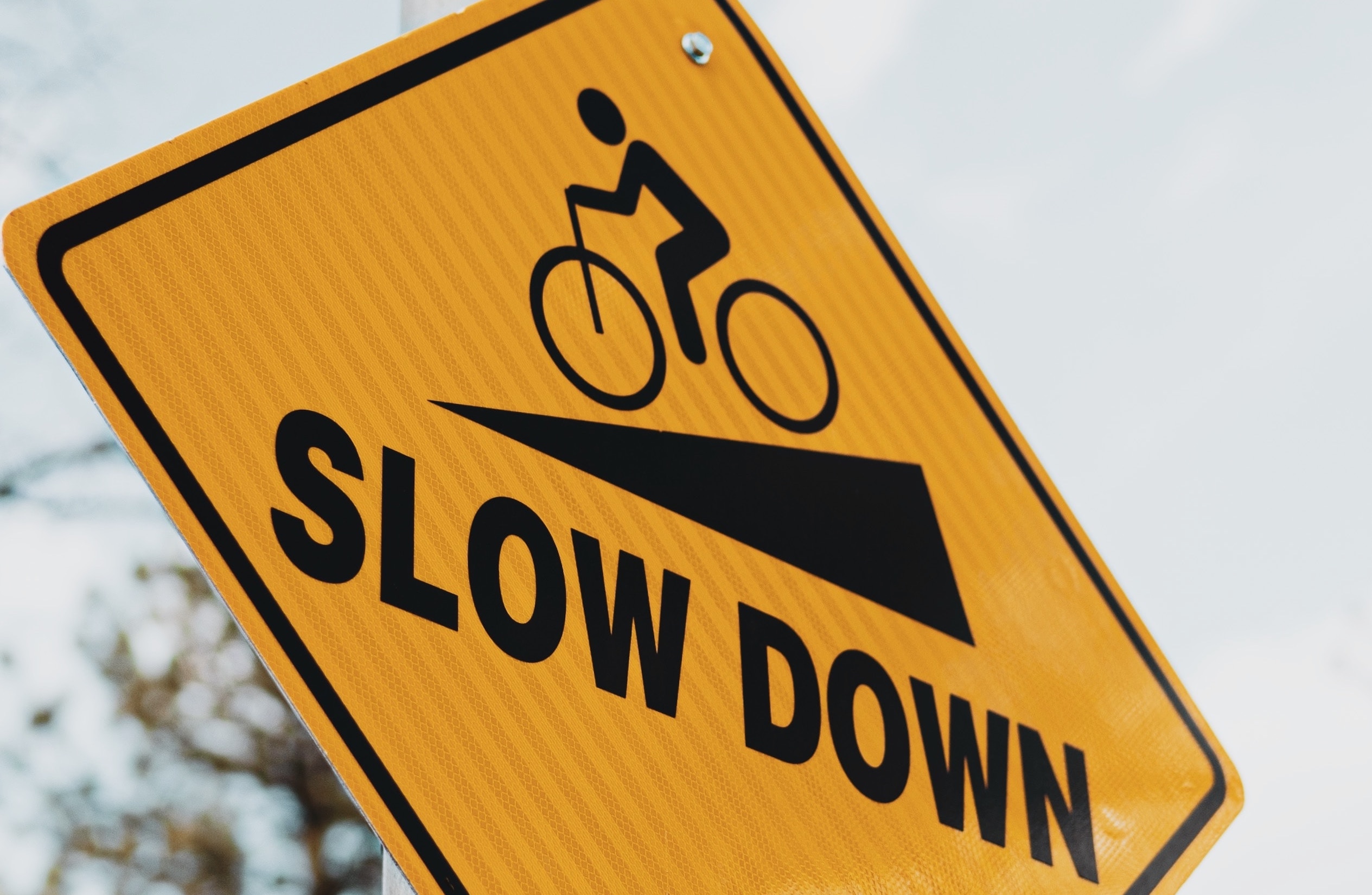 a yellow slow down sign on a pole