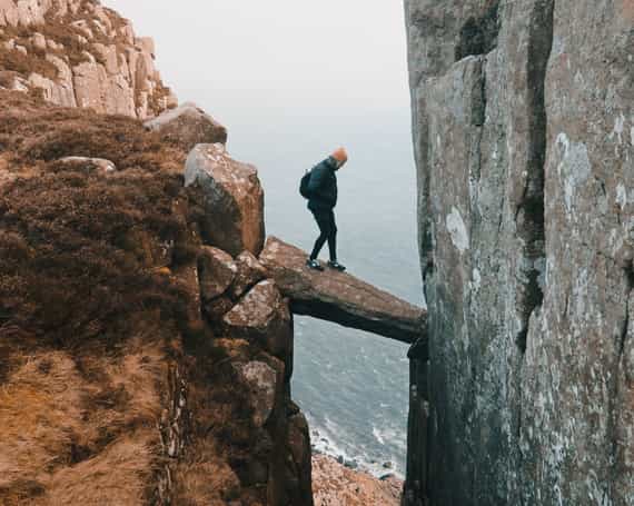 Image showing someone being risky by crossing a path between two cliffs on a rock leaning between them.