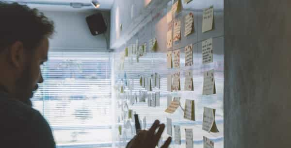 A man looking at sticky notes on a wall.