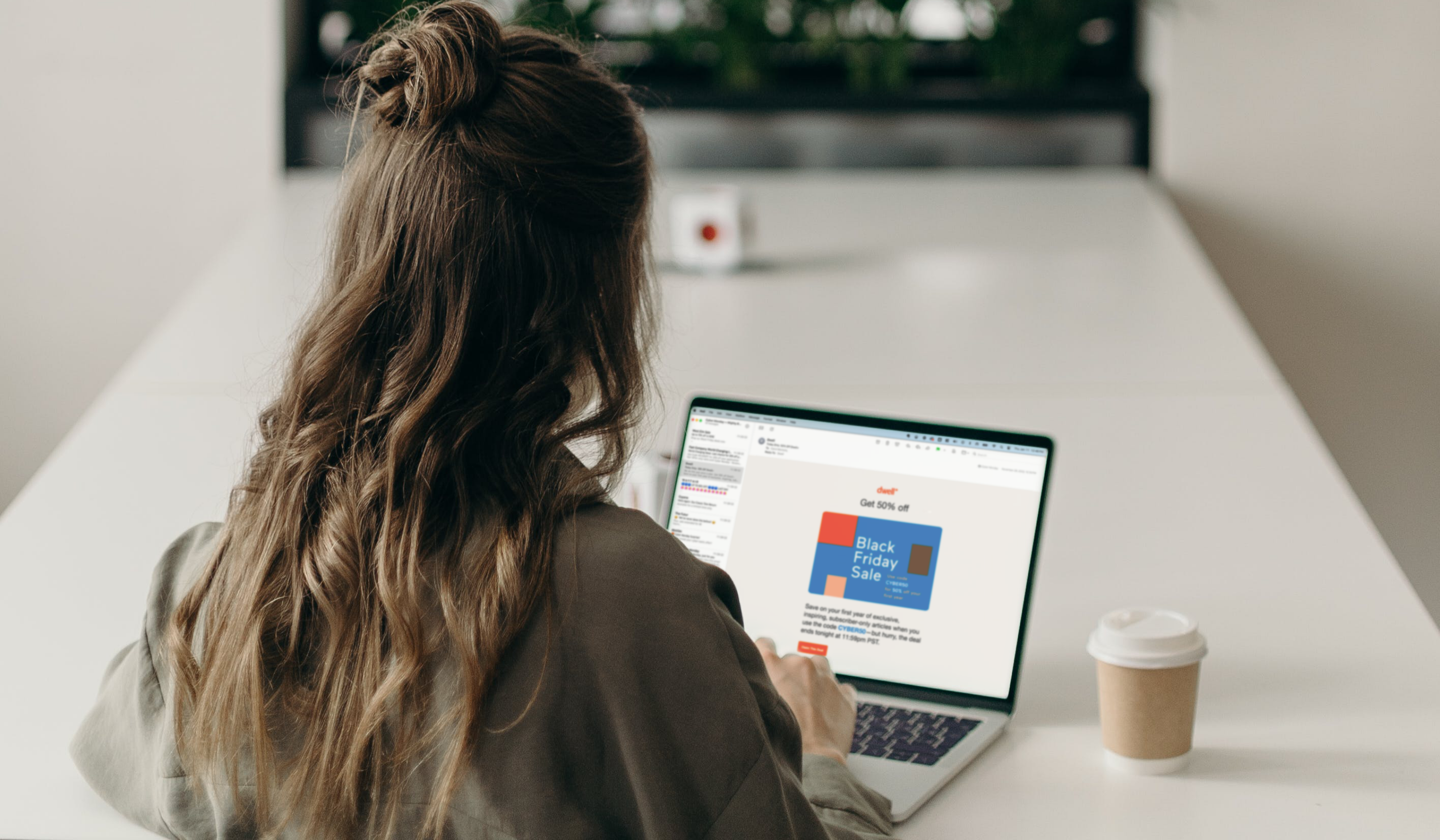 A woman engrossed in email marketing, sits at a desk with a laptop in front of her.