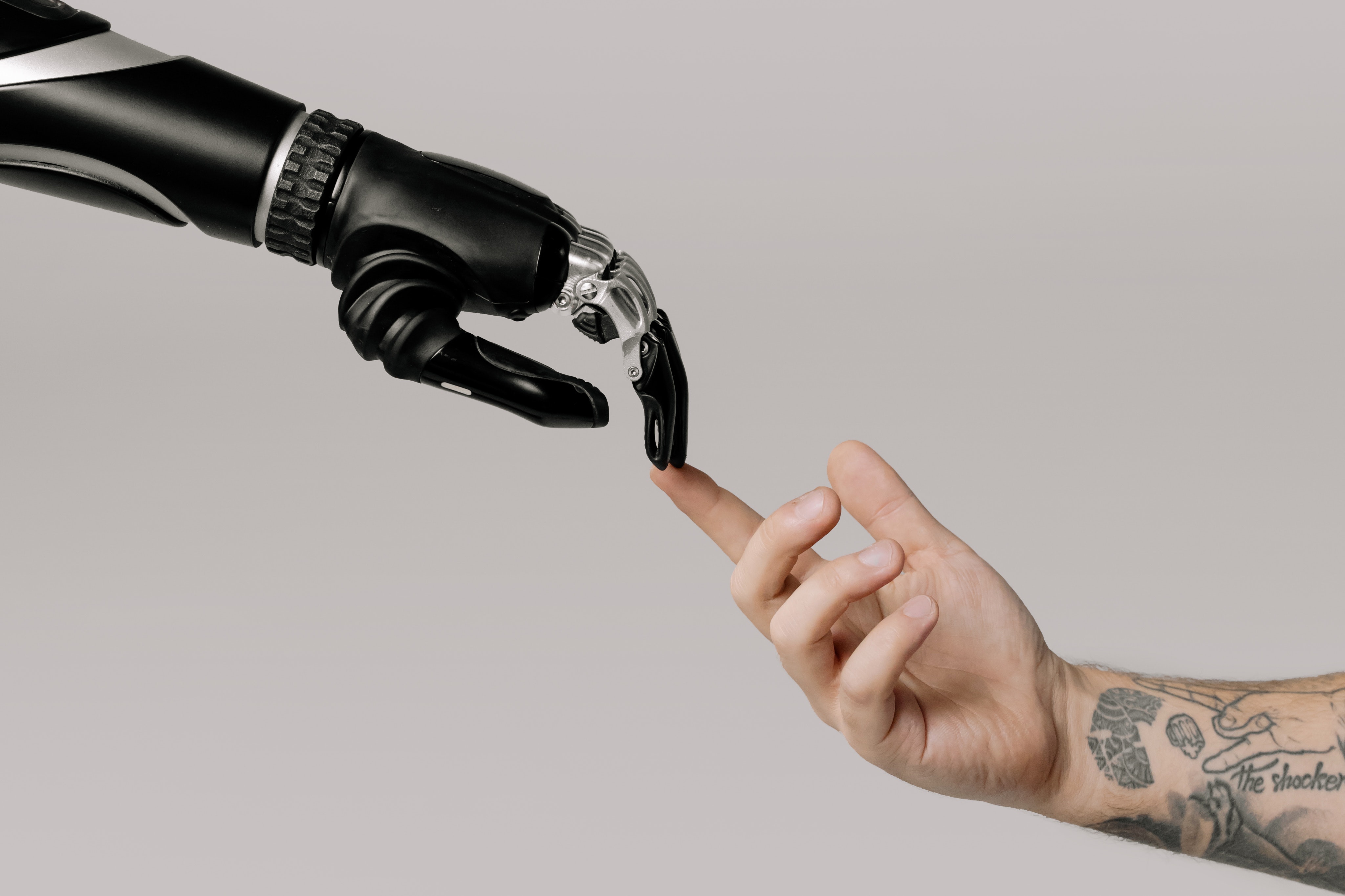 a man with a tattoo on his arm is touching his index finger to the index finger of a robot